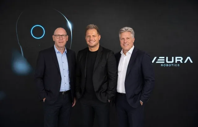 Three executives standing together in front of a NEURA Robotics-branded backdrop, marking the Adlatus Robotics acquisition