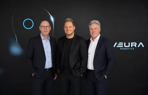 Three executives standing together in front of a NEURA Robotics-branded backdrop, marking the Adlatus Robotics acquisition