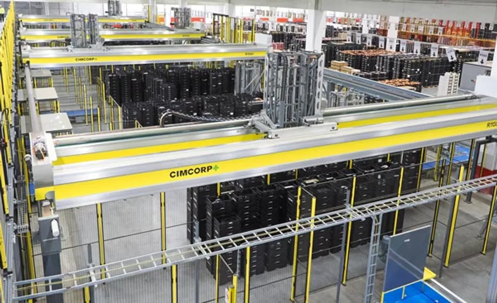 An overhead view inside a distribution center showing multiple parallel yellow, CIMCORP-branded overhead gantry rail robots picking black plastic tote crates above rows of warehouse racking.