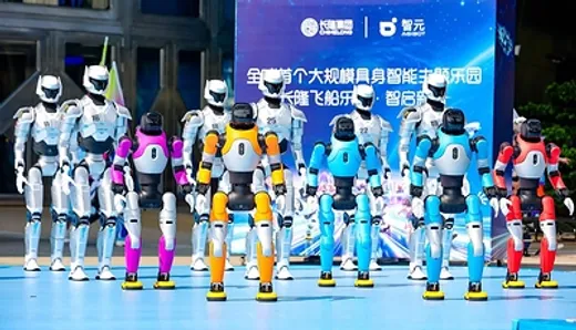 A lineup of about eight humanoid robots with different colored torsos and limbs (white, pink, blue, orange, red) standing on an event stage in front of a Chinese-language launch banner.